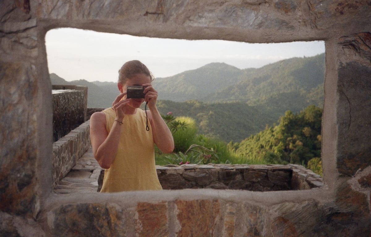 Antonia taking a photo through a stone window, mountains behind